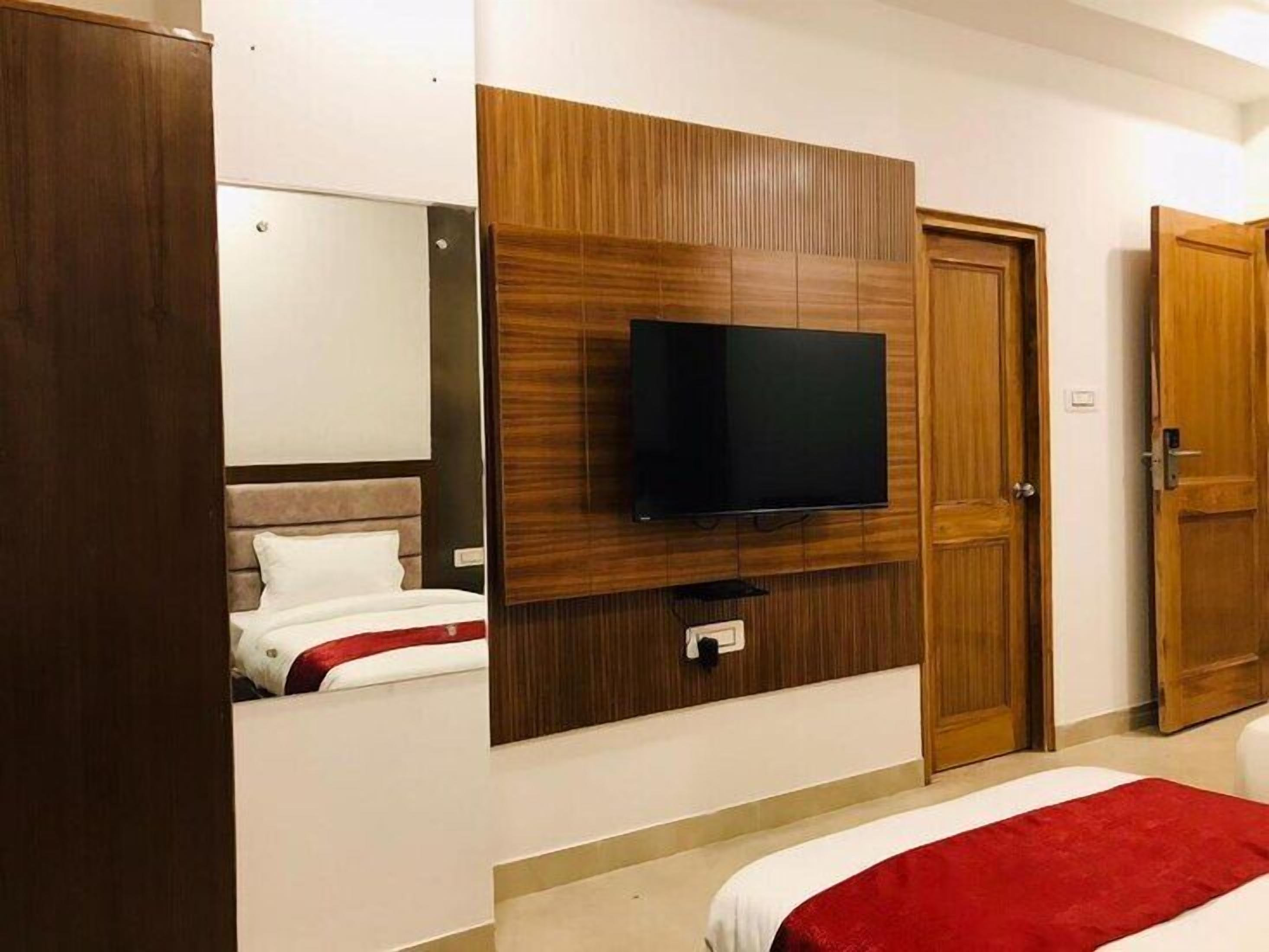 Una habitación de hotel con una cama, un televisor montado en un panel de madera y una puerta.