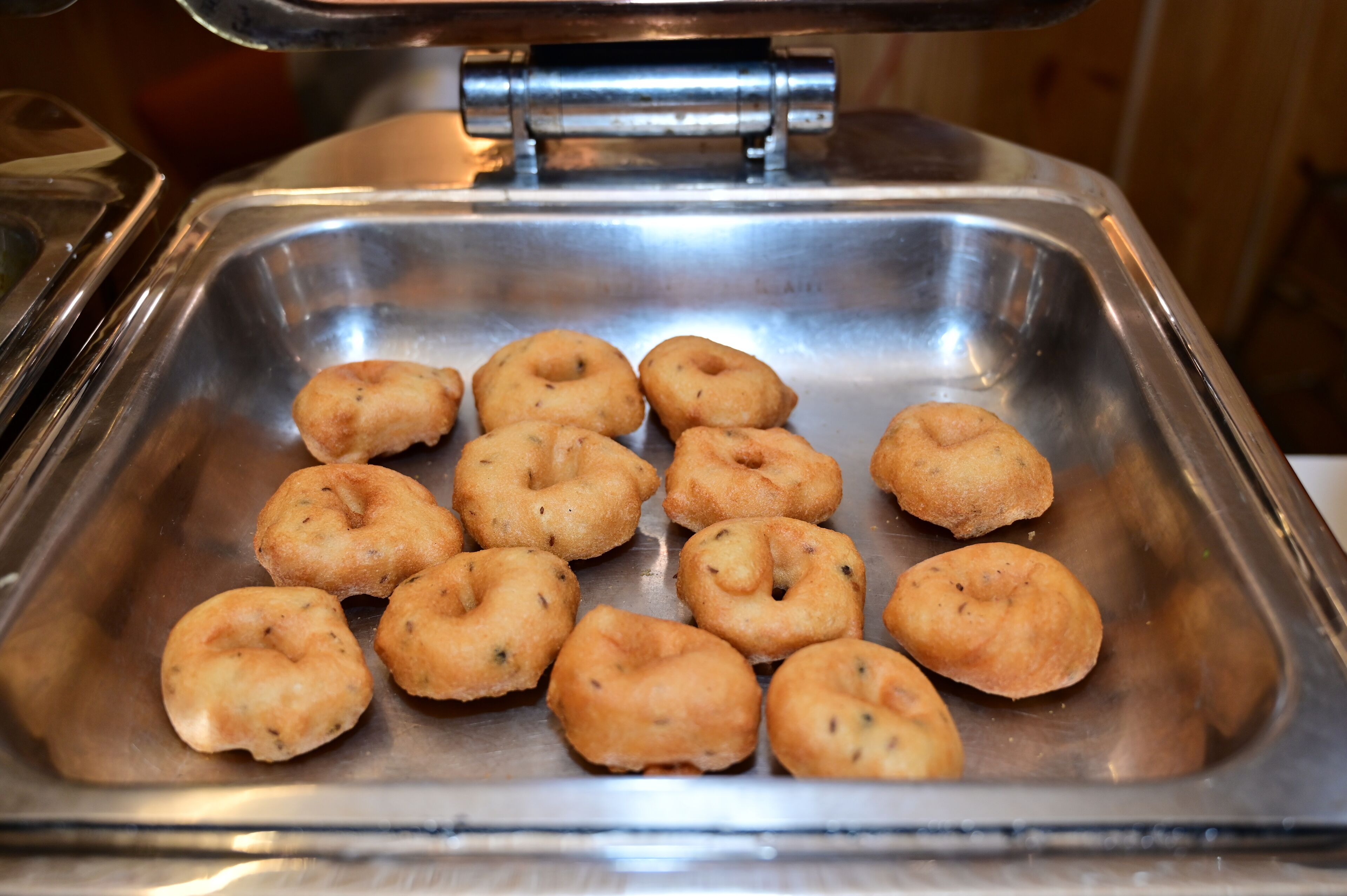 Een roestvrijstalen schaal met verschillende goudbruine gebakjes.