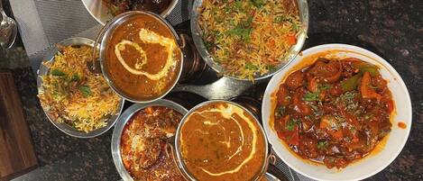 A variety of Indian dishes served on metal plates.
