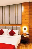 Una habitación de hotel con una cama, una mesita de noche con un teléfono y una lámpara de pared.
