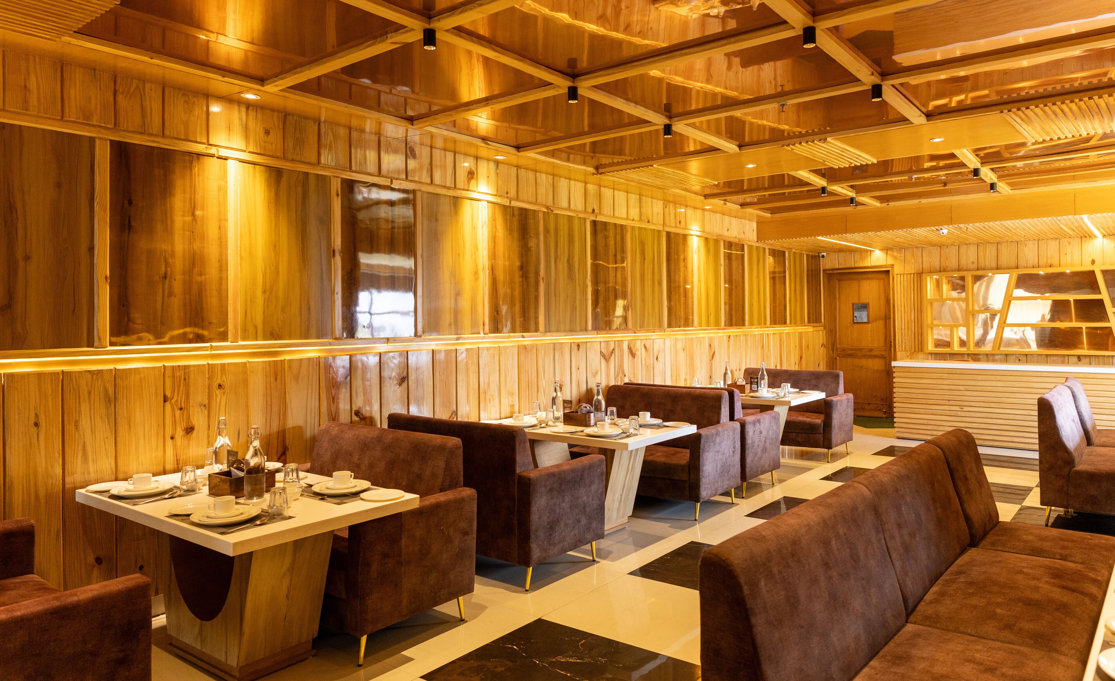 Un restaurante con paneles de madera, suelo a cuadros y asientos tapizados en tonos marrones.