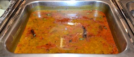 A buffet with a variety of dishes, including a prominent orange-colored curry and a clear soup.