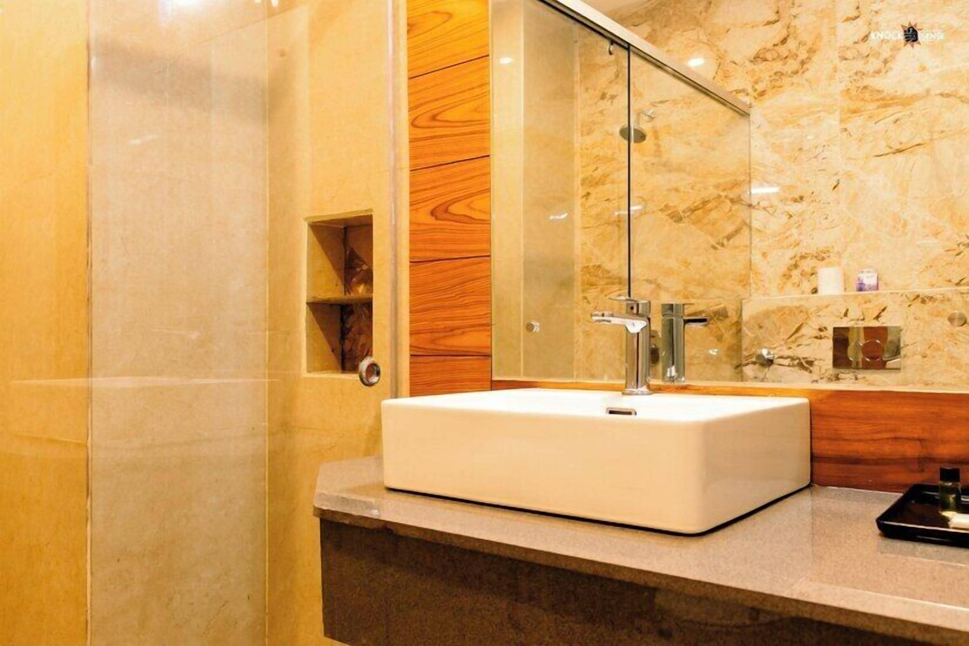A modern bathroom with a white sink, a glass shower enclosure, and a wooden vanity.