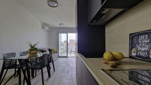 A modern kitchen with a blackboard displaying a motivational quote, a dining area with a glass table and chairs, and a view of the city through a glass door. - Modern Comfort With a View and Terrace (San Michele al Tagliamento)