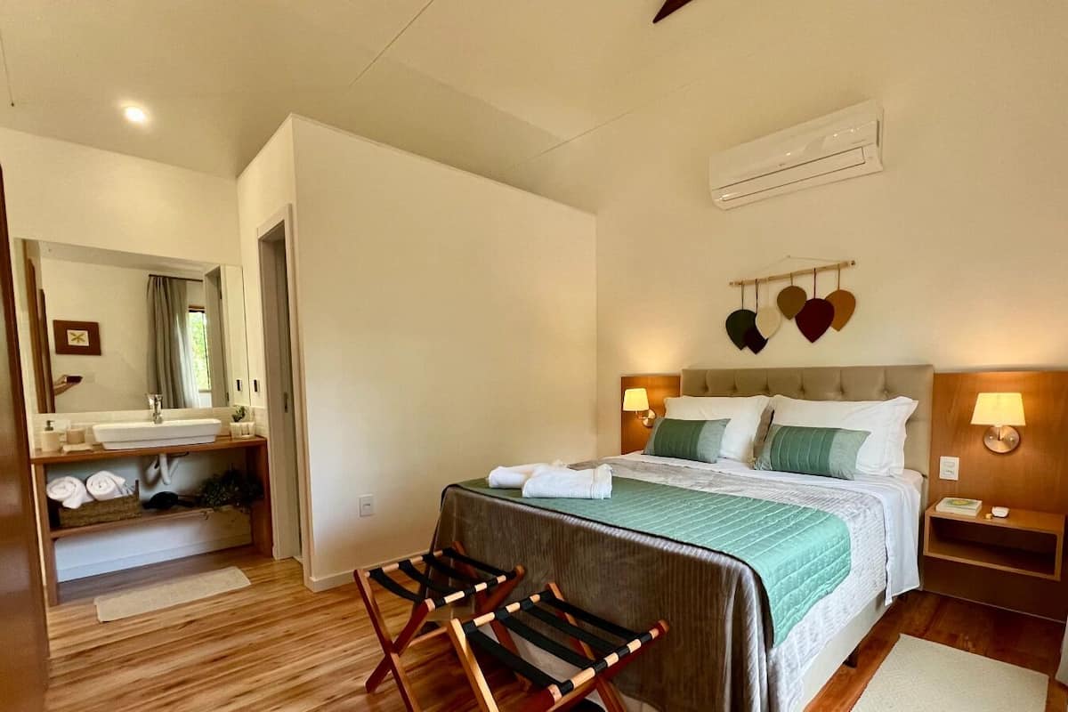 Een hotelkamer met een bed, nachtkastjes, een spiegel, een badkamer met wastafel en douche.