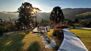 Un parque con un banco de madera, un sendero pavimentado y una zona verde con árboles.