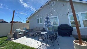 Ein Garten mit Terrasse, Gartenmöbeln, Grill und Lichterketten.