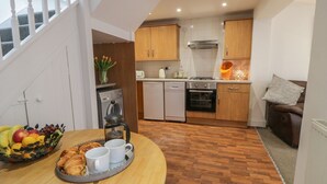 Een kleine keuken met houten kastjes, een vaatwasser, een oven en een gasfornuis.