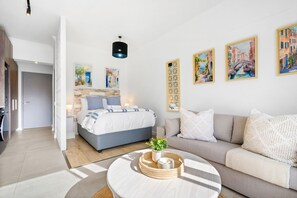 A modern hotel room with a bed, sofa, and a round coffee table with decorative items.