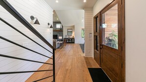 Un interior moderno con una escalera de madera, un comedor y una puerta de madera.