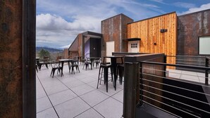 Terraza en la azotea con mobiliario exterior y vistas a las montañas.