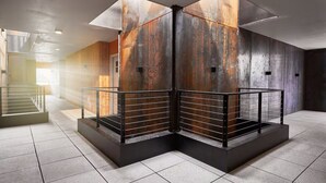 Un interior moderno con una escalera de esquina, barandillas de metal y una combinación de paredes de madera y metal.