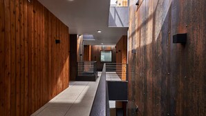 Un pasillo moderno con paneles de madera, barandilla de metal y suelo de baldosas.