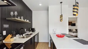 Una cocina moderna con una isla central, muebles de color blanco y negro, e iluminación colgante.