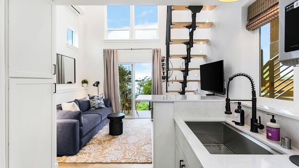 A modern kitchen with a built-in stove, a sink, and a flat-screen TV. - Covelet Hideaway (Blaine)