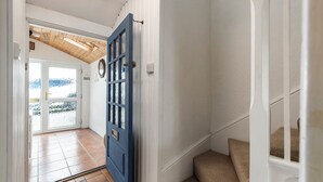 A hallway with a blue door, a staircase, and a view of the outdoors. - Melbourne - Sea Views and Parking (Saundersfoot)