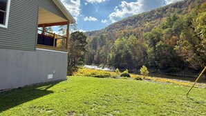 Een huis met een balkon met uitzicht op een rivier en een beboste heuvel.