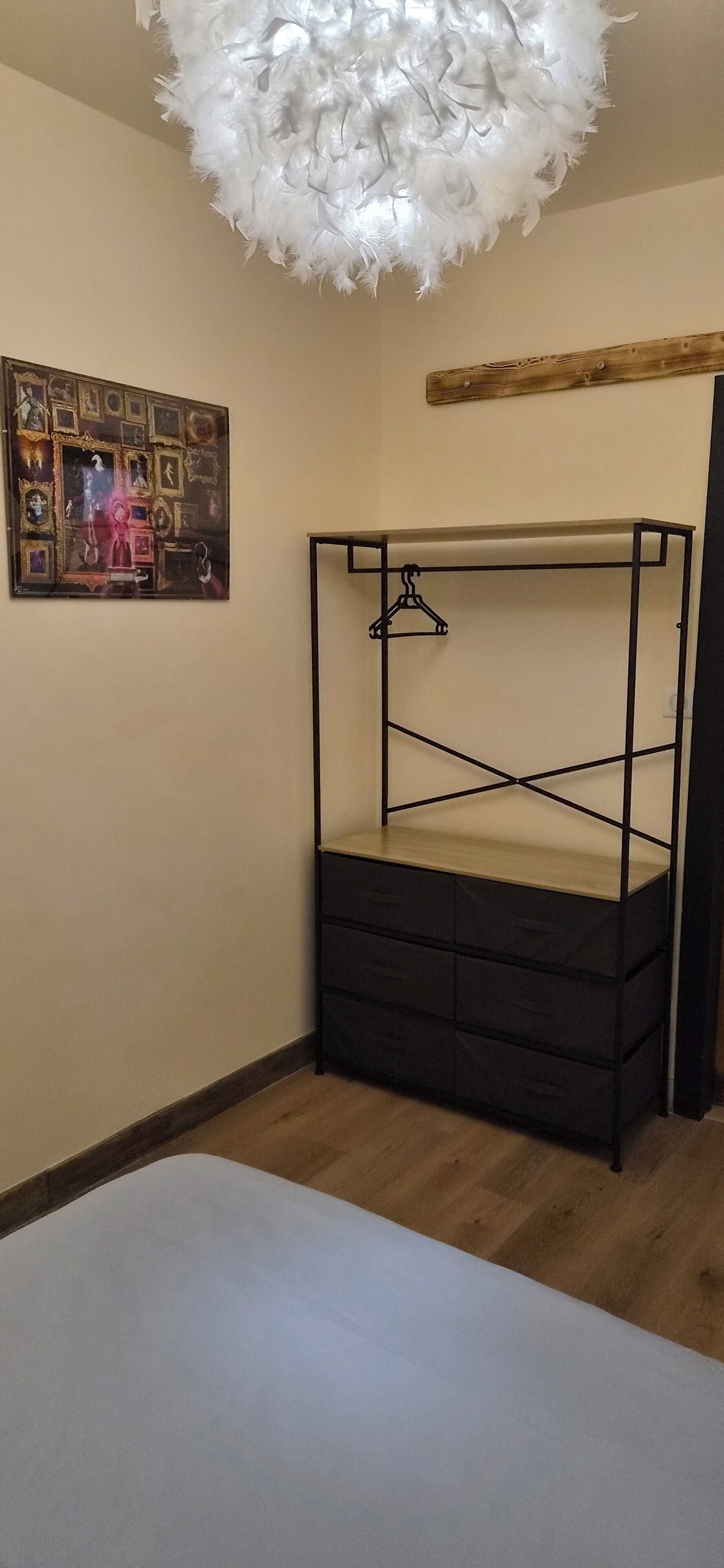 Una habitación con una cama litera, una viga de madera en el techo, un cuadro colgado en la pared y una lámpara colgante.
