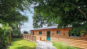 A wooden cabin with a stone pathway leading to the entrance. - Owl Lodge (Liskeard)