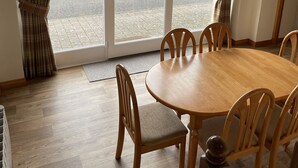 A dining area with a wooden table and chairs, a glass door leading outside, and a wooden floor. - The Clocktower (Perth)