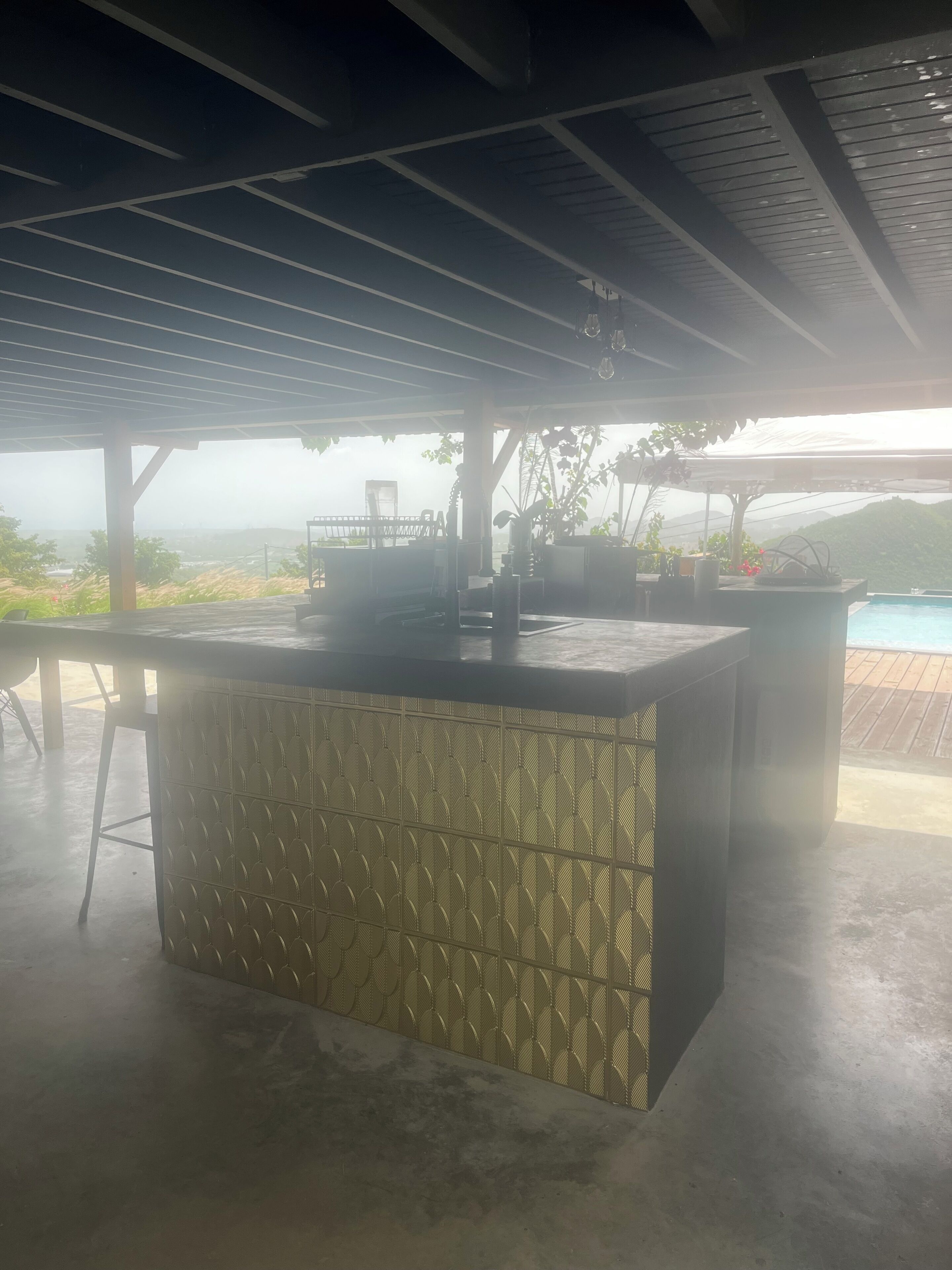 Un espacio al aire libre cubierto con barra, asientos y vistas al paisaje.