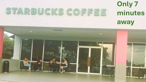 En Starbucks Coffee med glasfacade og mennesker siddende udenfor.