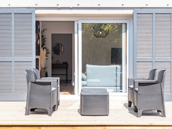 An outdoor seating area with wicker furniture and a glass door leading to a room.