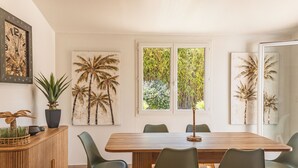 A dining area with a wooden table and four chairs, a potted plant, and artwork on the walls. - Villa Meia Di Porto-Vecchio (PORTO VECCHIO)