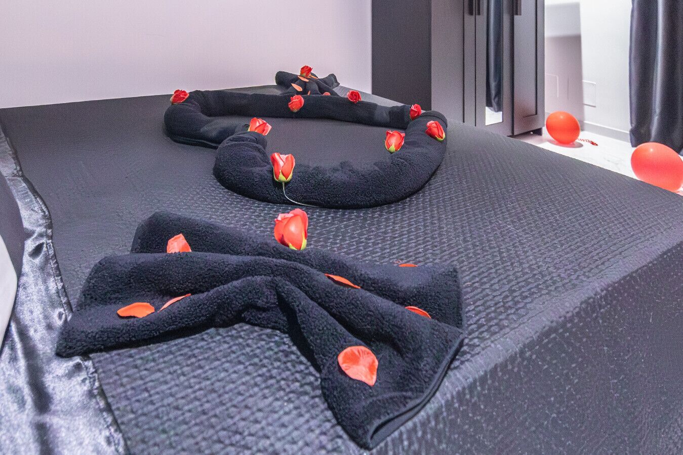 Une table de massage bien rangée, avec des serviettes noires et des pétales de rose.