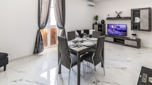 A modern dining area with a marble floor, a dining table set for four, and a TV on the wall. - Amour - House, Private Jacuzzi (Rosolini)