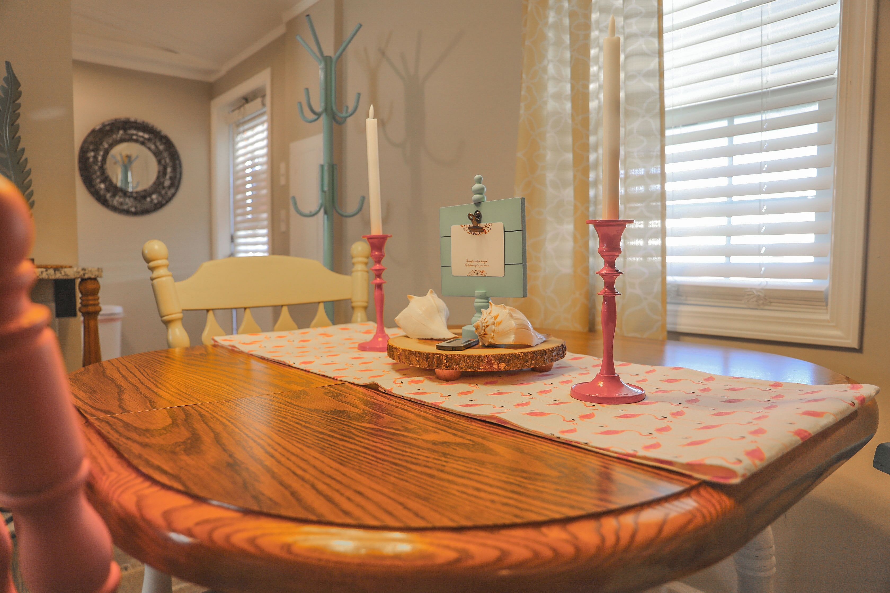 A wooden dining table with a placemat, candles, and a small decorative item.