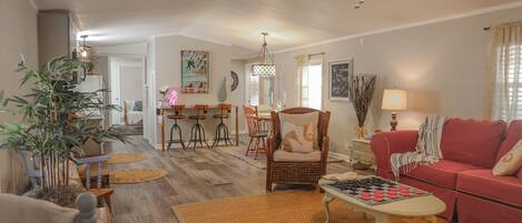 A spacious living room with a red sofa, a wooden coffee table, and a dining area with a chandelier.