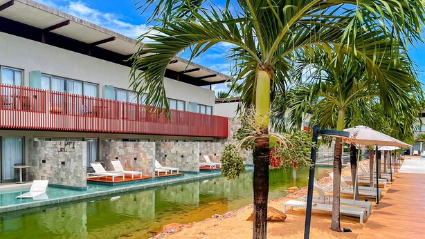 A modern hotel with a pool, lounge chairs, and palm trees. - Flat Île de Pipa Taiti - By Almare (Tibau do Sul)