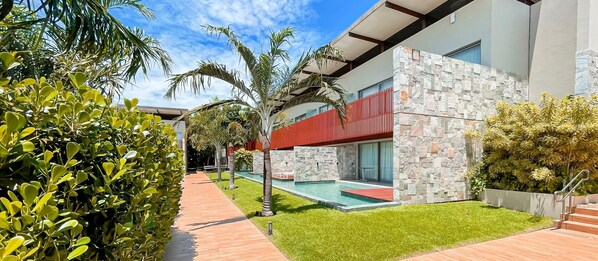 A modern building with a swimming pool, surrounded by well-maintained greenery and a clear sky. - Flat Île de Pipa Taiti - By Almare (Tibau do Sul)