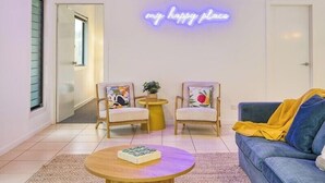 A living room with two chairs, a sofa, a coffee table, and a neon sign that reads "my happy place". - 24 Nautilus - Tangalooma - Moreton Island (moreton island)