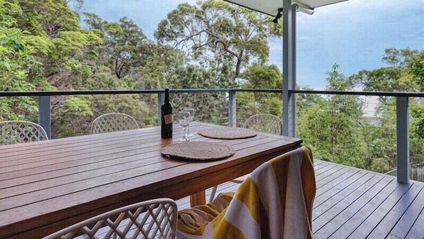 A wooden deck with a table and chairs, a bottle of wine, and a glass on the table. - 24 Nautilus - Tangalooma - Moreton Island (moreton island)