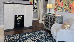 A living room with a fireplace, a television, a colorful painting, and a patterned rug. - 🍒CHERRY’S DELIGHT - Where timeless comfort is served with a cherry on top! (Glasgow)