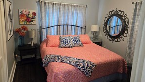 A bedroom with a bed, a ceiling fan, a nightstand, a lamp, a mirror, and a painting on the wall. - 🍒CHERRY’S DELIGHT - Where timeless comfort is served with a cherry on top! (Glasgow)