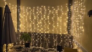 A cozy indoor seating area with string lights, a wooden bench, and a small garden with pebbles and plants. - Dream Lagos B&B (Lagos)