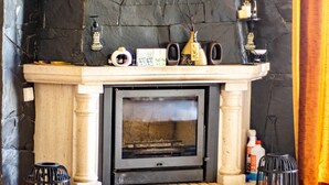 A fireplace with a stone mantle, two black candle holders, and a small shelf with decorative items. - Dream Lagos B&B (Lagos)