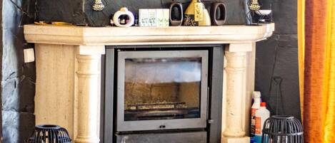 A fireplace with a stone mantle, two black candle holders, and a small shelf with decorative items.