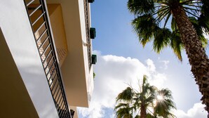 A building with a balcony, a palm tree, and a clear sky with clouds. - Dream Lagos B&B (Lagos)