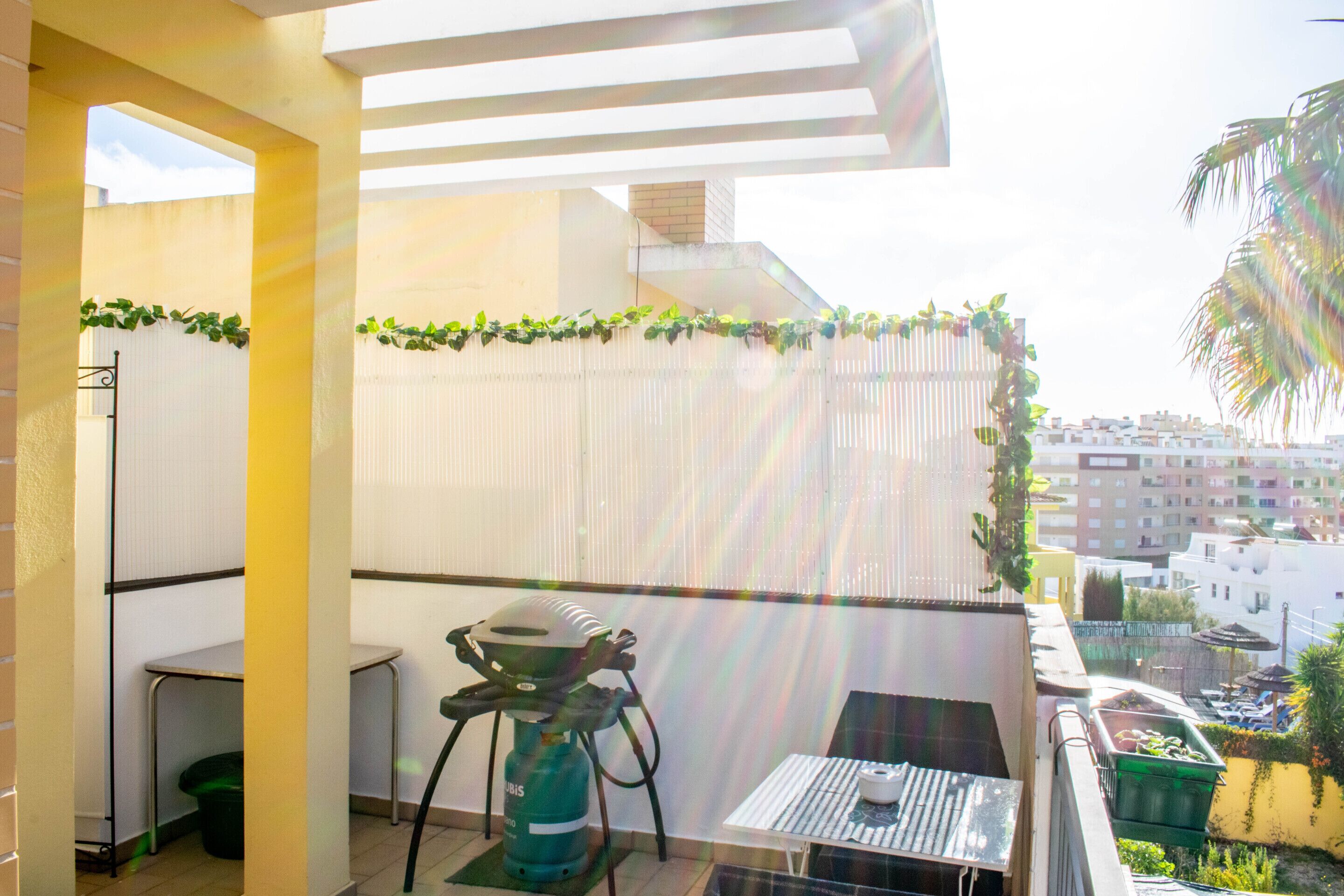 Un balcón con mesa, sillas, una parrilla y vista panorámica de la ciudad.