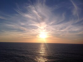 A sunset over a calm sea with a clear sky.