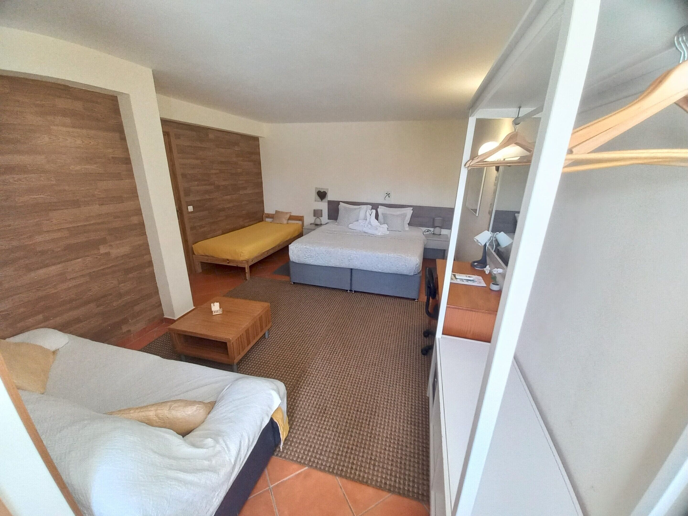 A hotel room with a bed, a sofa, a small table, and a wardrobe.