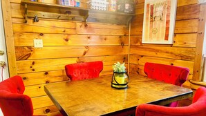 A wooden-paneled room with a wooden table and red upholstered chairs. - 3 bdrm 2 BA cabin with WiFi, AC near Surry, Hopewell, Wakefield& Prince George (Spring Grove)