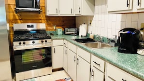 A compact kitchen with a gas stove, microwave, toaster, and coffee maker. - 3 bdrm 2 BA cabin with WiFi, AC near Surry, Hopewell, Wakefield& Prince George (Spring Grove)