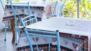 A dining area with tables covered by patterned tablecloths and blue chairs.
