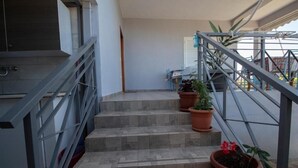 A staircase with a metal railing, potted plants, and a view of a balcony area.