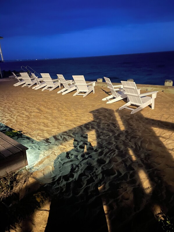 A beach with white lounge chairs arranged in rows facing the ocean.